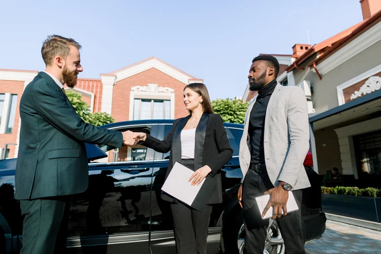 A private chauffeur welcoming a guest into a luxury vehicle